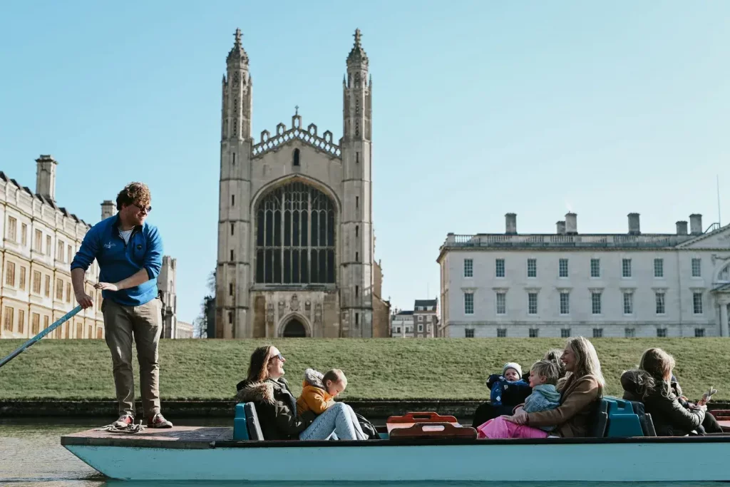 A family with children in a punting boat with King's College Chapel, an impressive stone building, in the background.