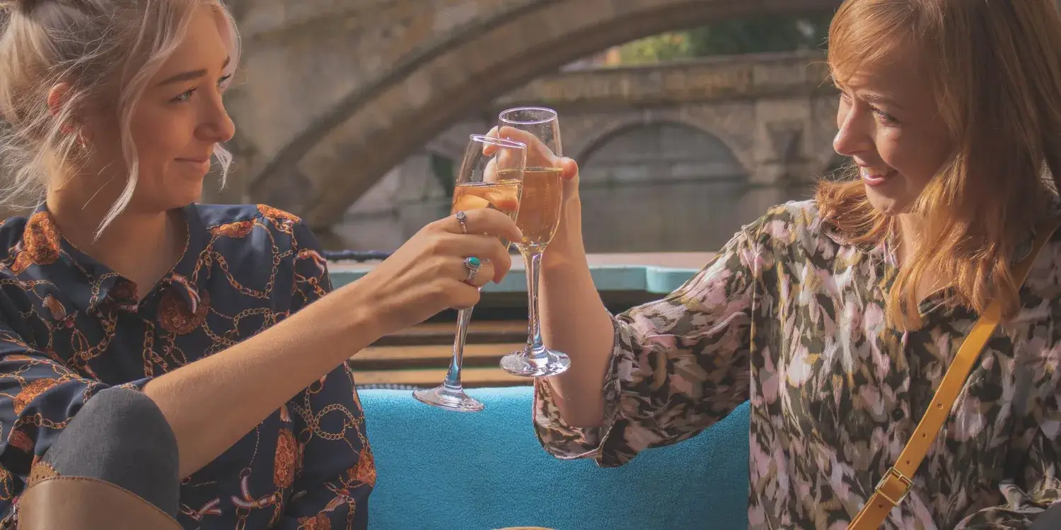 Two young women smiling and toasting champagne glasses.