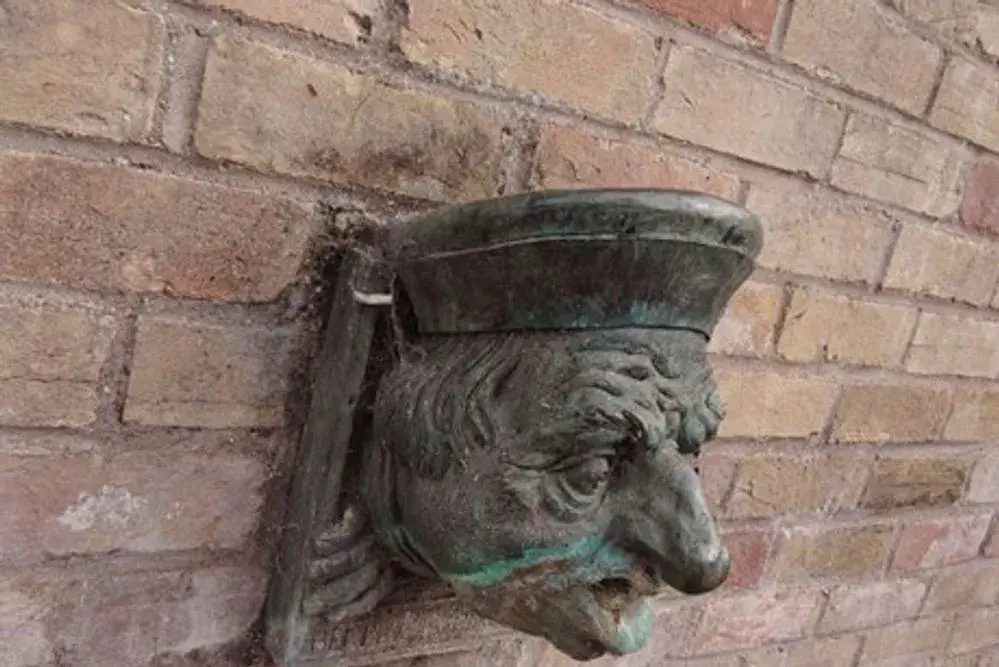The bust of Benedict Spinola, a peculiar head with a long nose and bulging eyes. The bust is cast in metal and appears to be emerging from the wall on which it's attached.