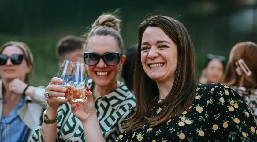 Two young women smiling and toasting glasses.