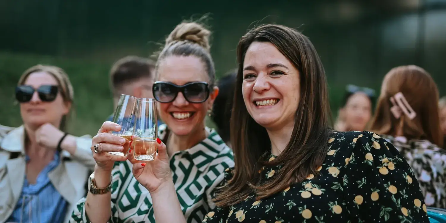 Two young women smiling and toasting glasses.