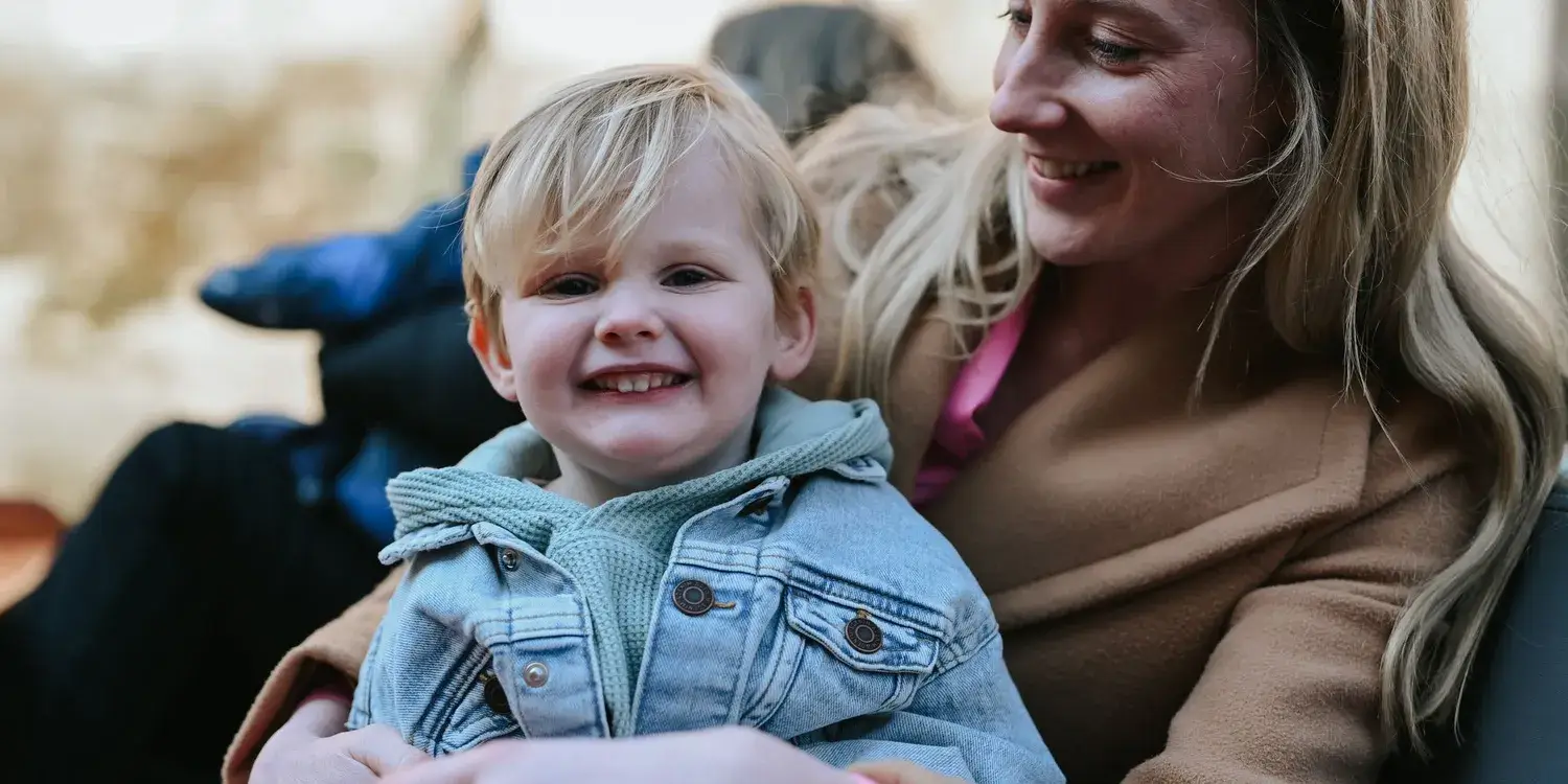 A mother and child smiling and sitting in a punting boat.