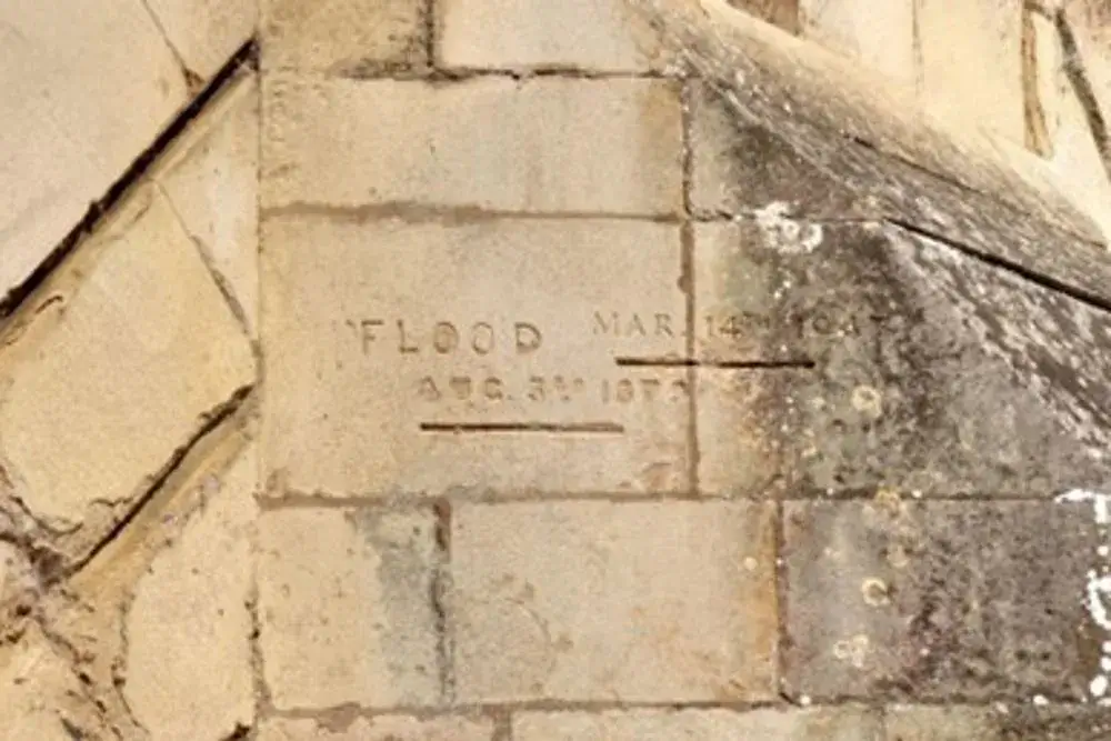 Flood markers carved into the stonework of a bridge, marking where the waters rose to on certain years.