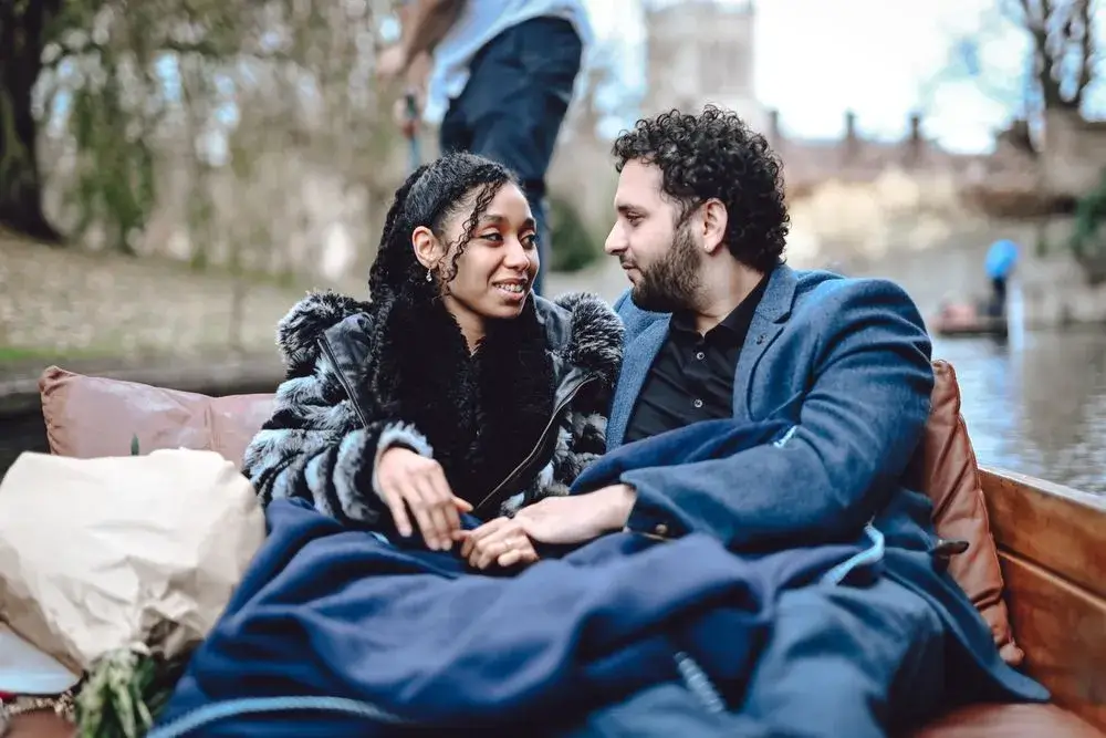 A young couple sitting in a punting boat and gazing into each others eyes.