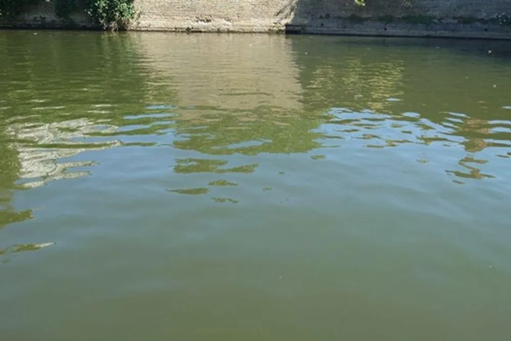 A close-up of the river, showing a distorted reflection of a stone building on the bank.