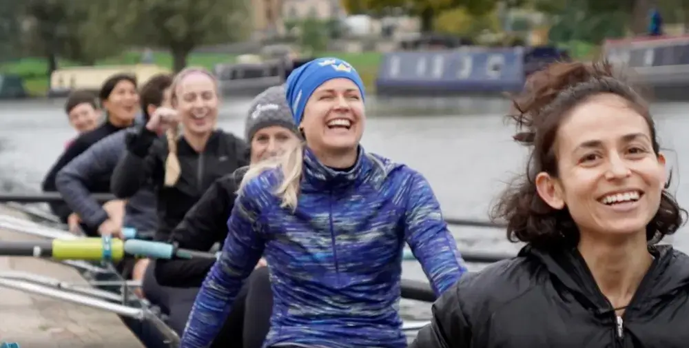 People sitting in a rowing boat, smiling and laughing.