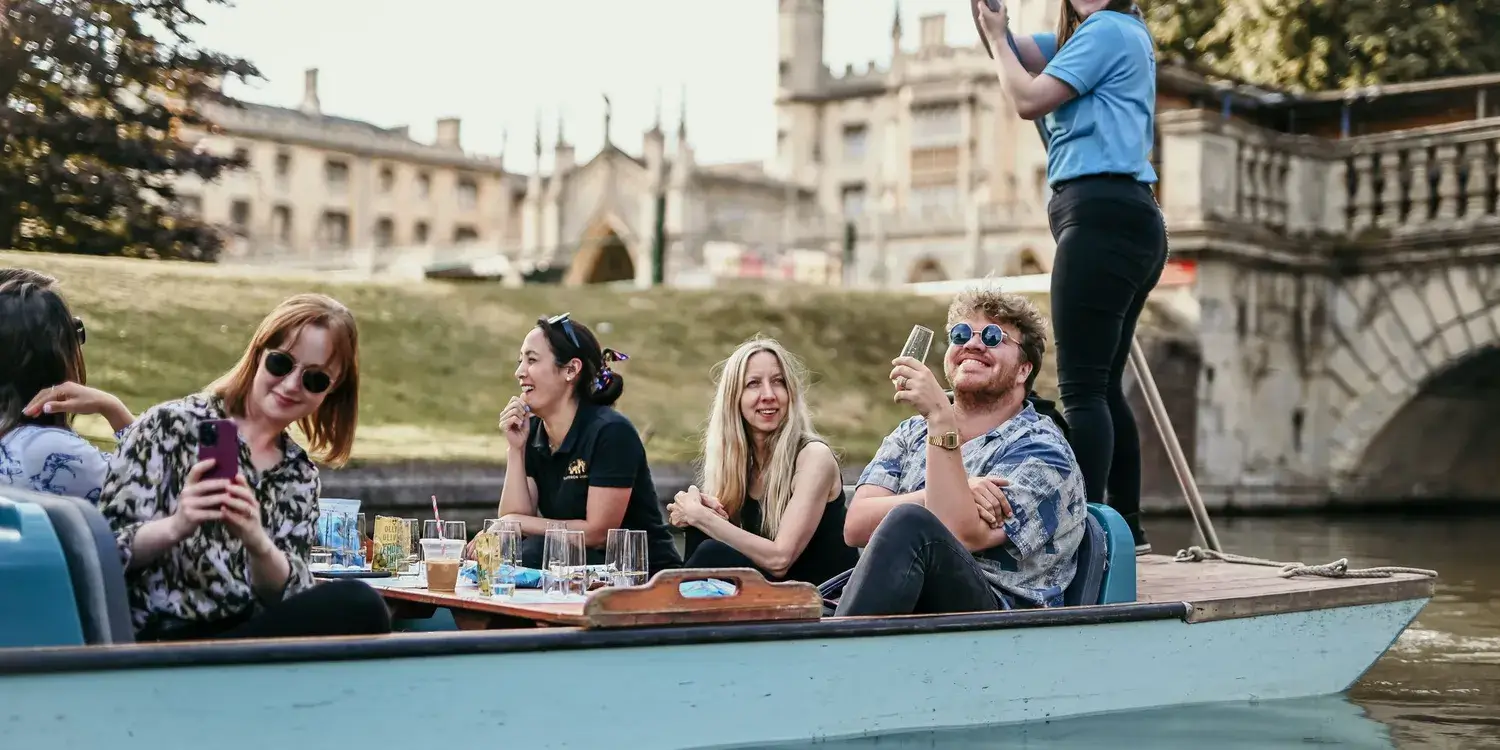 A party of people enjoying drinks in a punting boat.