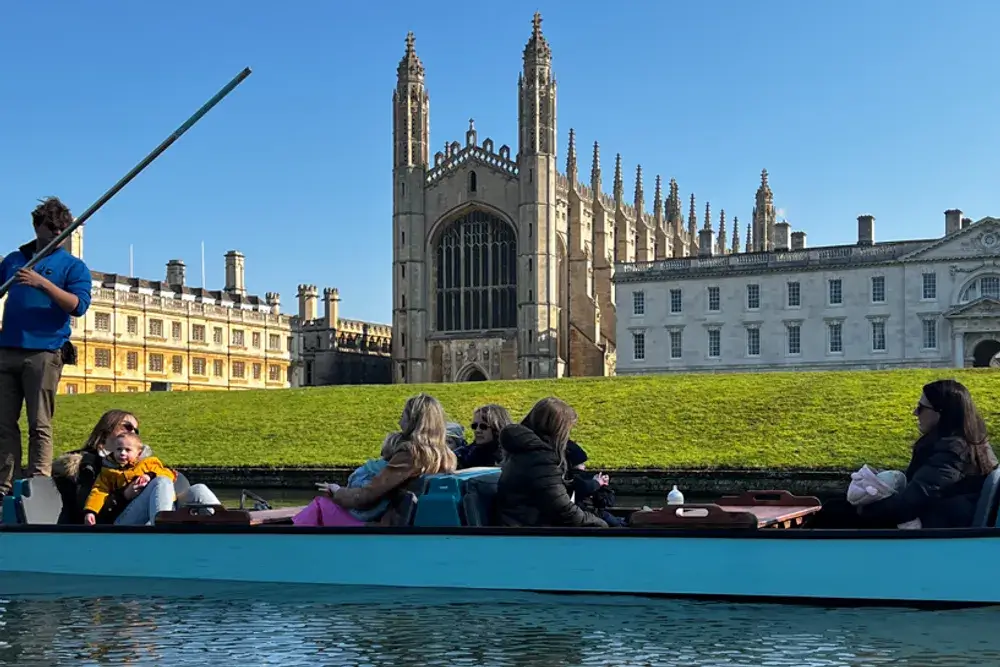 A family with children in a punting boat with Kings College Chapel, an impressive stone building, in the background.