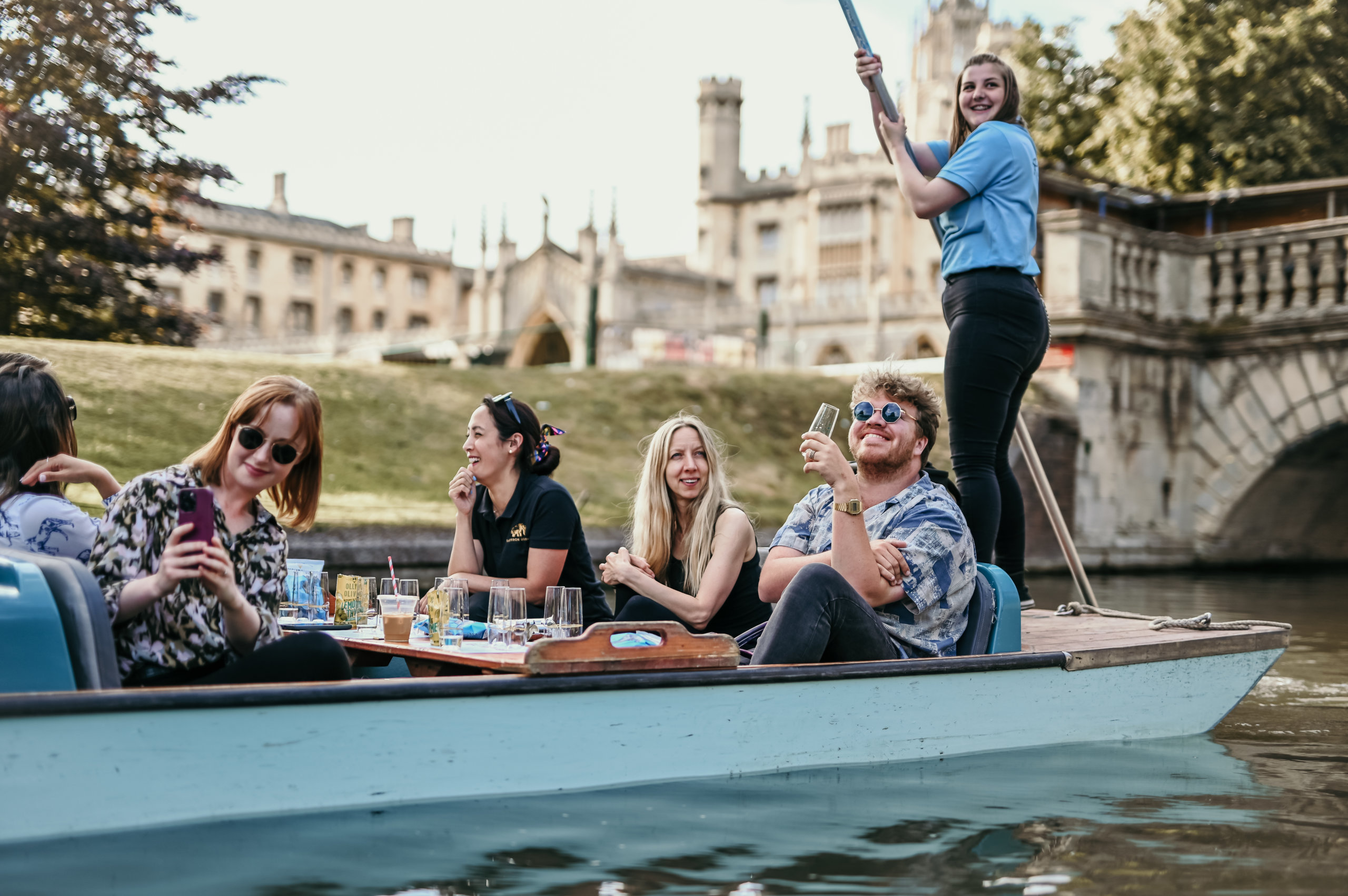 A party of people enjoying drinks in a punting boat.