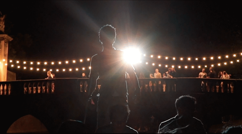Man standing under lit up bridge