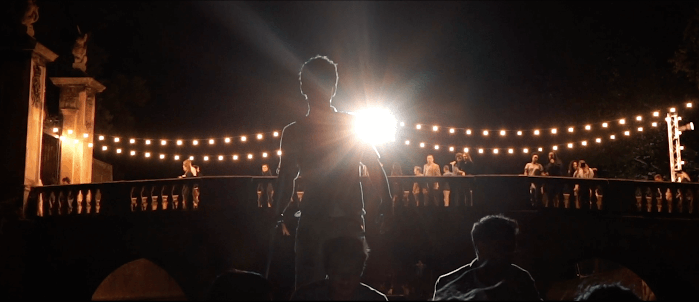 Man standing under lit up bridge